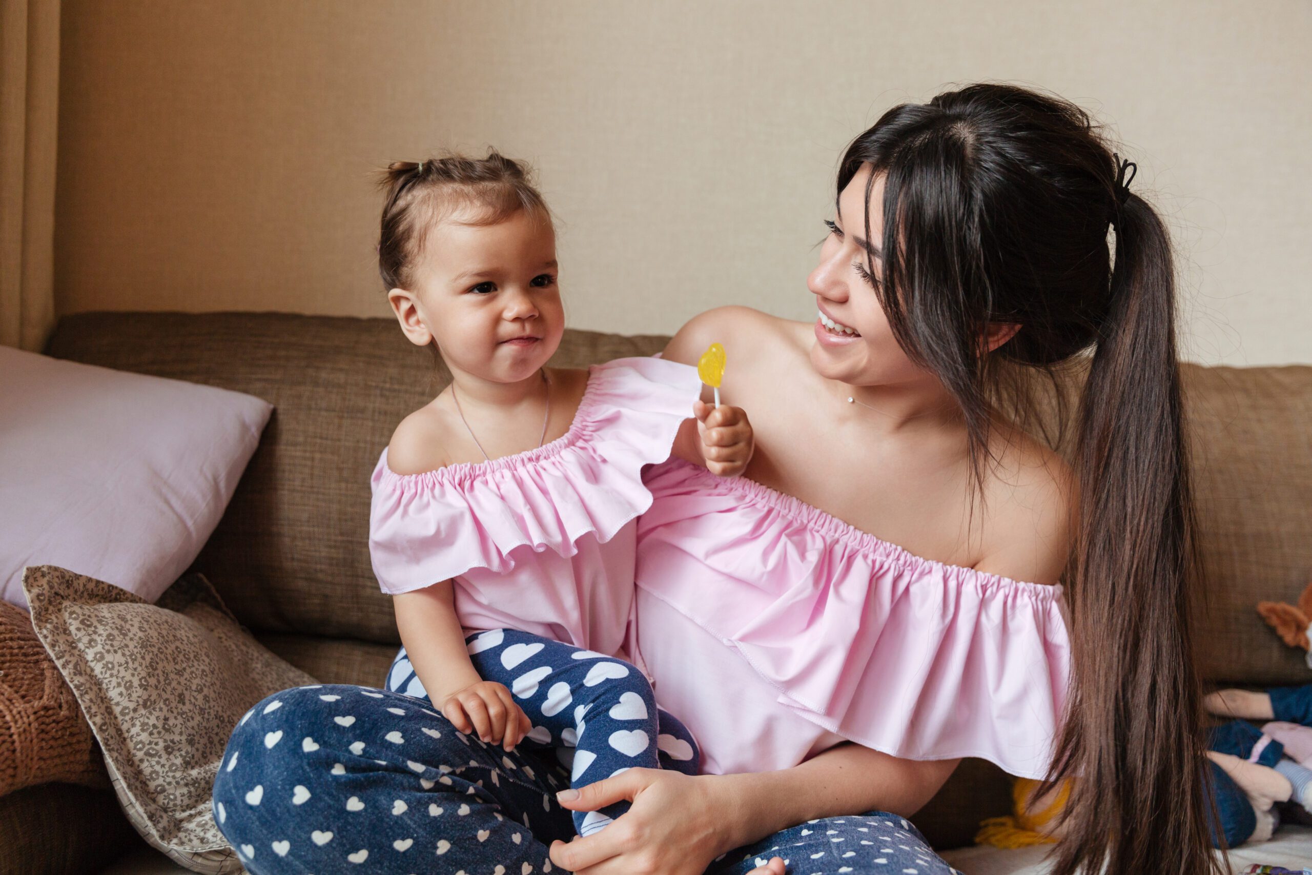 picture of young mother sitting on sofa with her little daughter indoors looking aside SBI 321514088 1 2 scaled